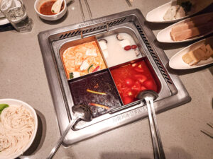 Hot pot divided into four sections with Sichuan, Tom Yum, Chicken, and Tomato soup bases
