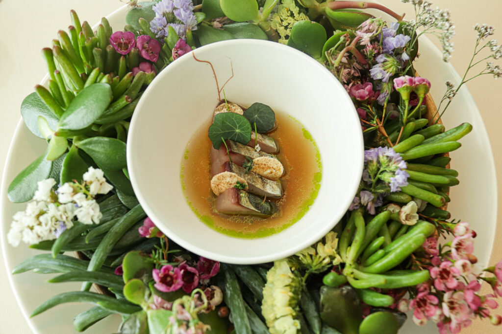 Bowl of Bonito, Mushroom broth on a bed of fresh greenery and flowers