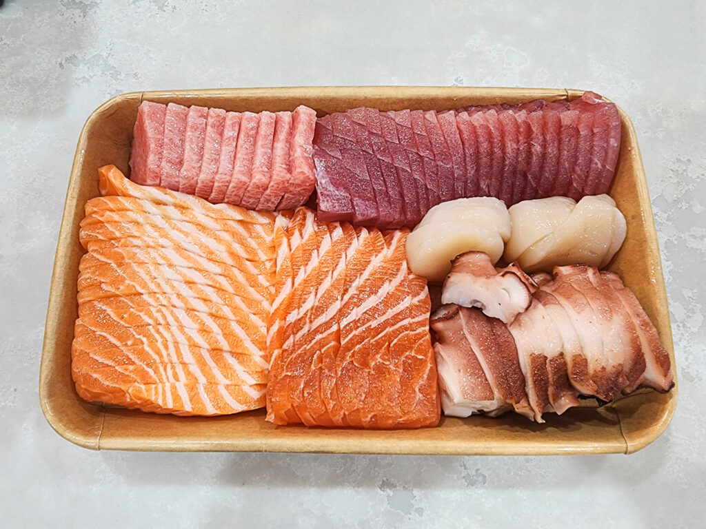 Sliced salmon sashimi, tuna sashimi, octopus, and otoro made fresh to order in a takeaway container