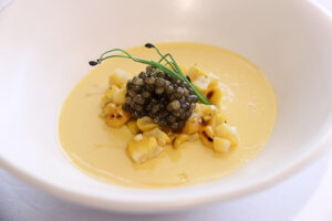 Sencha infused corn custard, charred corn kernels, topped with caviar in a ceramic bowl